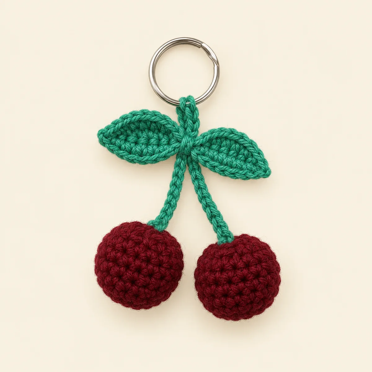 Handmade crochet cherry keychain with two maroon cherries and green leaves on a key ring