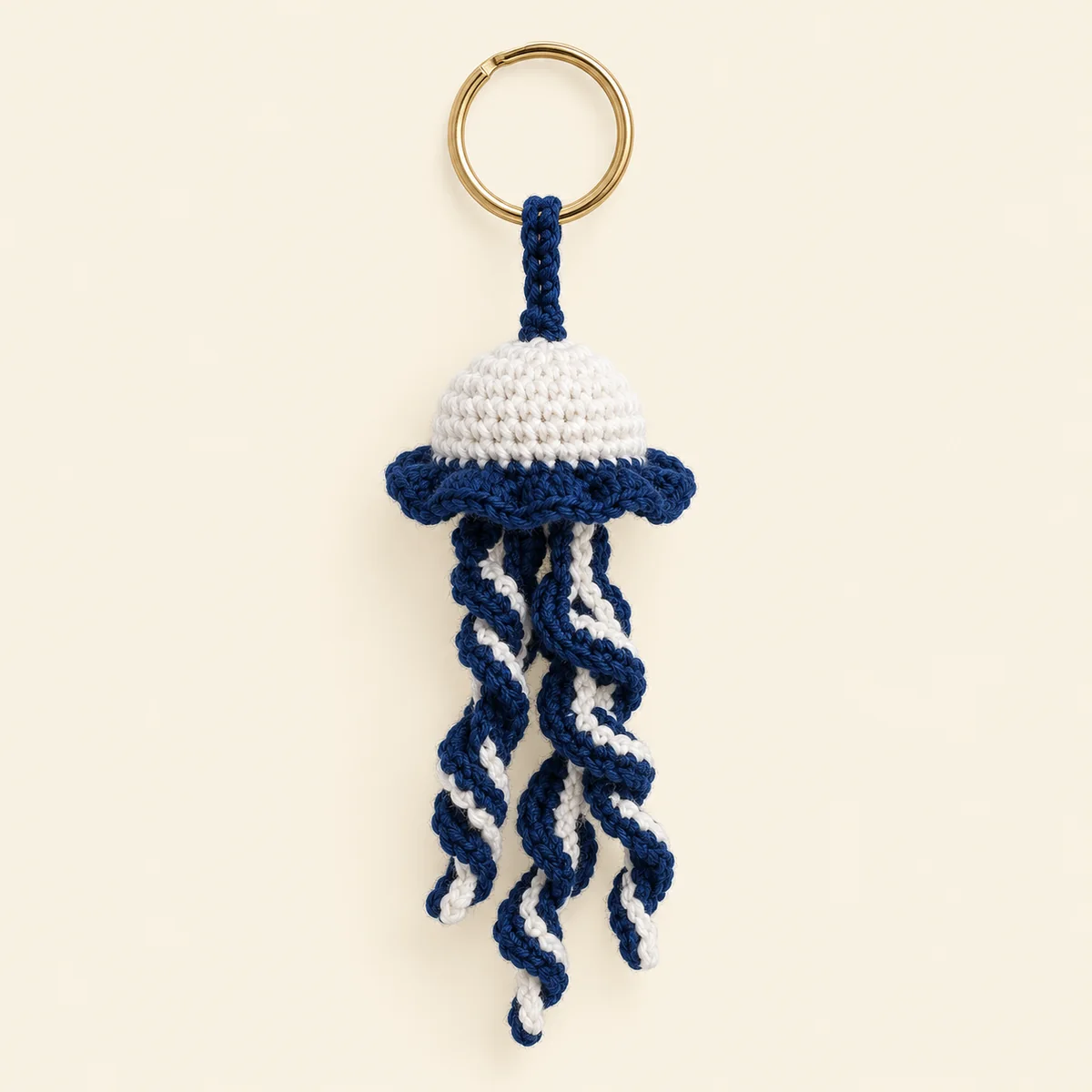 Handmade crochet jellyfish keychain in white and navy with trailing tentacles on a key ring