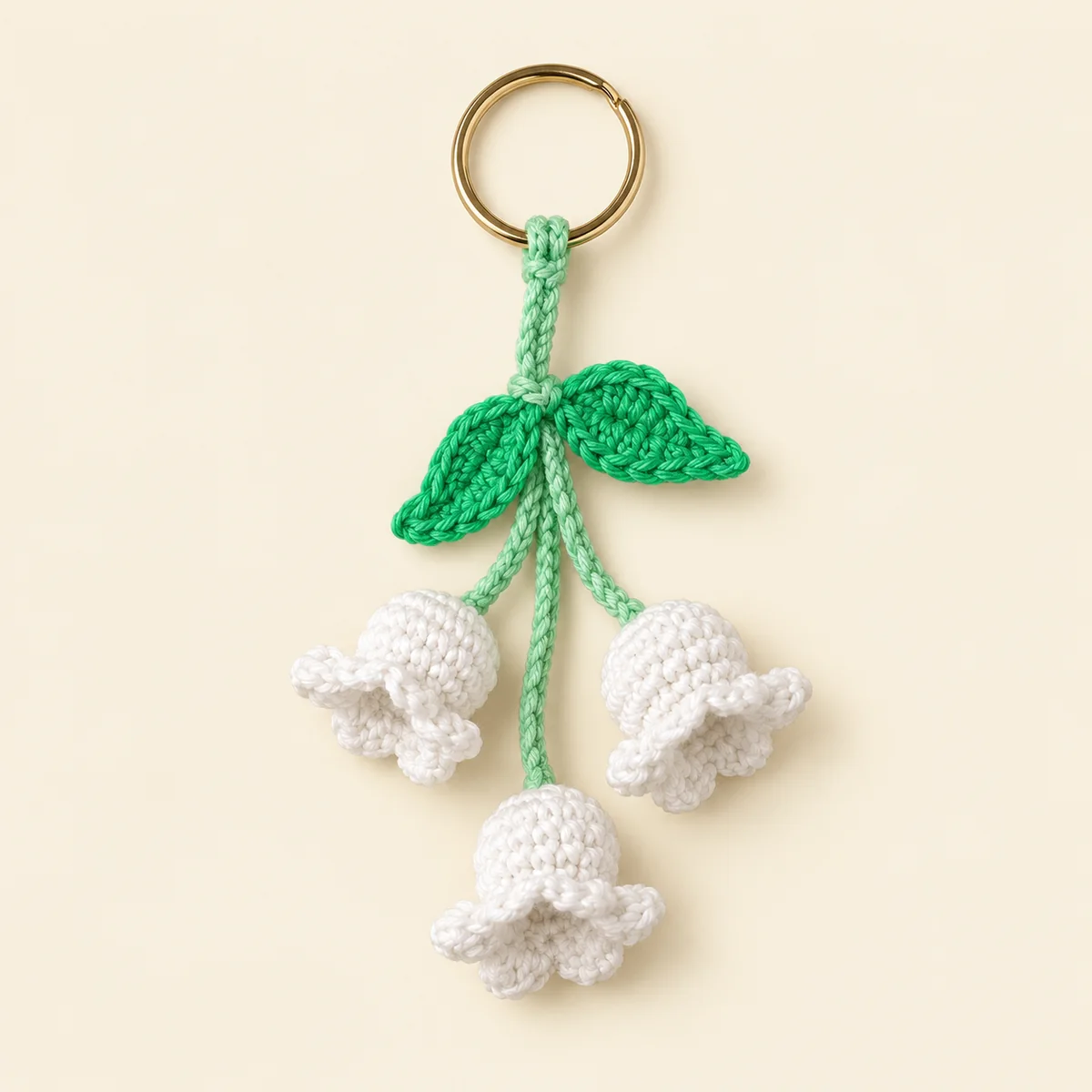 Handmade crochet lily of the valley keychain with white bell flowers and green leaves on a key ring